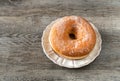 Sweet fried donut covered with sugar on plate on the old wooden background