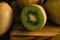 Sweet fruit on a dark background. Half kiwi macro and whole fruit on wooden cutting board