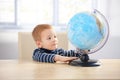 Sweet ginger-haired little boy studying globe