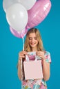 Sweet girl with baloons and little prersents bag in the hands on the blue background. Royalty Free Stock Photo