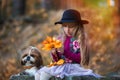 Sweet girl in a hat weaves a wreath of autumn maple leaves. Royalty Free Stock Photo