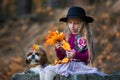 Sweet girl in a hat weaves wreath of autumn maple leaves Royalty Free Stock Photo