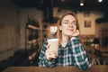 Sweet girl sits with a cup of coffee in her hand in a cafe with her eyes closed and smiles. Attractive girl resting in the coffee Royalty Free Stock Photo