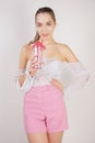 Sweet girl in transparent blouse, summer funny plaid shorts and pink high heels posing with a glass cup of water on white backgrou Royalty Free Stock Photo