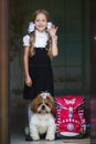 Sweet girl with white bows in a school uniform with a cute little dog.