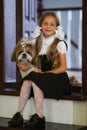 Sweet girl with white bows in a school uniform with a cute little dog.