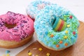 Sweet glazed donuts decorated with sprinkles on board, closeup. Tasty confectionery