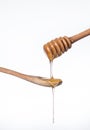 Sweet Golden honey flows down a wooden stick on a wooden spoon on a white background