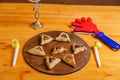 Sweet gomentashi cookies on a wooden board next to a clapper for the Purim holiday