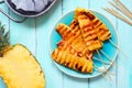Grilled summer pineapple wedges, above view table scene over blue wood