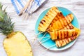 Grilled summer pineapple wedges, top down table scene over white wood