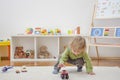 Sweet happy child boy having fun playing with cars and many colorful toys, on the floor, at home Royalty Free Stock Photo