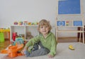 Sweet happy child boy having fun playing with cars and many colorful toys, on the floor, at home Royalty Free Stock Photo