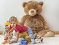 Sweet happy child boy having fun playing with his giant teddy bear and many colorful toys, indoor at home Royalty Free Stock Photo