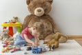 Sweet happy child boy having fun playing with his giant teddy bear and many colorful toys, indoor at home Royalty Free Stock Photo