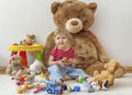 Sweet happy child boy having fun playing with his giant teddy bear and many colorful toys, indoor at home Royalty Free Stock Photo