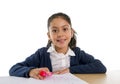 Sweet happy latin child sitting on desk doing homework and smiling