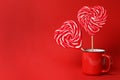 Sweet heart shaped lollipops in cup on red background, space for text. Valentine`s day celebration Royalty Free Stock Photo