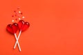 Sweet heart shaped lollipops and sprinkles on coral background, flat lay with space for text. Valentine`s day celebration Royalty Free Stock Photo