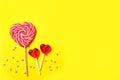Sweet heart shaped lollipops and sprinkles on yellow background, flat lay with space for text. Valentine`s day celebration Royalty Free Stock Photo