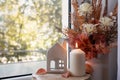 Sweet Home. Still life details in home on a wooden window. Autumn decor on a window, dried flowers, candle and toy house Royalty Free Stock Photo