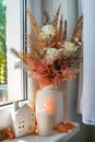 Sweet Home. Still life details in home on a wooden window. Autumn decor on a window, dried flowers, candle and toy house Royalty Free Stock Photo