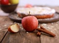 Sweet homemade apple pie - fresh apples and cinnamon sticks in front of a homemade apple pie on a rustic wooden table Royalty Free Stock Photo