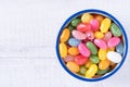 Sweet jelly beans in a ceramic bowl on a white wooden background with copy space. Colorful candy with mixed fruit flavor. Top view Royalty Free Stock Photo