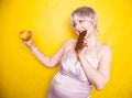 Sweet joyous curvaceous girl with a short haircut stands in a delicate evening silk dress and compares bad and good food Royalty Free Stock Photo