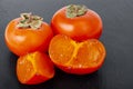 Sweet juicy orange persimmon on contrasting black background. Studio Photo Royalty Free Stock Photo