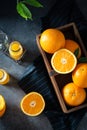 Sweet juicy oranges and pile of oranges in wooden basket, orange juice in bottles on dark table. Top view, flat lay. Healthy clean Royalty Free Stock Photo