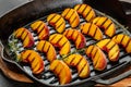 Sweet and juicy roasted peaches on a a grill pan on a dark background. top view