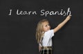 Sweet junior schoolgirl standing happy writing in blackboard I learn Spanish Royalty Free Stock Photo