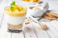 Sweet layered dessert with crushed graham crackers, cream cheese and pineapple curd, topped with fresh fruit slices in a glass jar