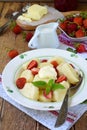 Sweet lazy pierogi. Ukrainian dumplings with sour cream, butter and strawberry on wooden background. Summer berry breakfast.