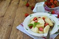 Sweet lazy pierogi. Ukrainian dumplings with sour cream, butter and strawberry on wooden background. Summer berry breakfast.