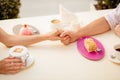 Sweet life together. Close up cropped photo of two young lovers, sitting in cafe and hold each other`s hands, having nice coffees