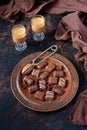 Sweet liqueur, chocolate candies in cocoa powder on dark table
