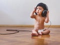 Sweet little baby boy with headphones, sitting on the floor and listening to music Royalty Free Stock Photo