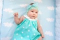Sweet little baby lying bed. She in blue dress with white stars, bow on head, top view Royalty Free Stock Photo