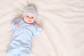 Sweet little baby in warm pajamas and hat lying on comfortable bed at home Royalty Free Stock Photo