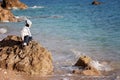 Sweet little boy, sitting on a big rock in the ocean, contemplating Royalty Free Stock Photo