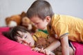 Sweet little boy, sleeping in the afternoon with his teddy bear, his brother bended over him, giving him a kiss Royalty Free Stock Photo