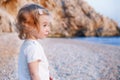 Sweet little caucasian baby girl with blond curly hair on sandy beach looking at blue sea.Happy,pretty,adorable,cute Royalty Free Stock Photo