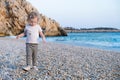 Sweet little caucasian baby girl with blond curly hair walking on sandy beach by blue sea.Happy,pretty,adorable,cute Royalty Free Stock Photo