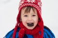 Sweet little child, boy, eating cookie in the snow winter time Royalty Free Stock Photo