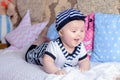 A sweet little child in a striped shirt and hats lying on the couch in the room Royalty Free Stock Photo