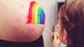 Sweet little daugter painting pregnant belly her mother. Baby birth expecting time and belly painting