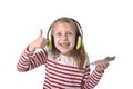 Sweet little girl with blonde hair listening to music with headphones and mobile phone singing and dancing happy Royalty Free Stock Photo