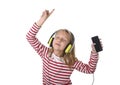 Sweet little girl with blonde hair listening to music with headphones and mobile phone singing and dancing happy Royalty Free Stock Photo